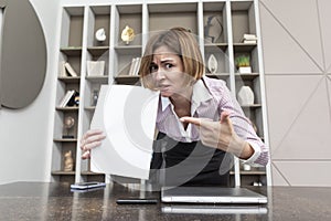 Tired frustrated and overworked business woman sitting in the office, holding documents and reading about problems in business