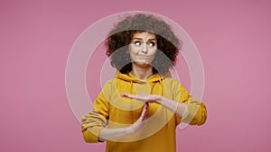 Tired girl afro hairstyle in hoodie looking with pleading frightened eyes and showing time out hands gesture