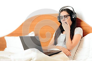 Yawning Sleepy Woman with Headphones and Laptop photo