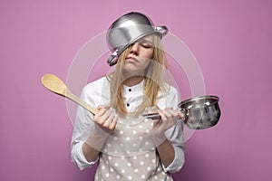 Tired girl cook in kitchen clothes with a pan on her head sleeps on a colored background, hard work of a housewife, lack of sleep