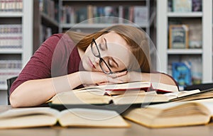 Tired girl with glasses having nap on books in library