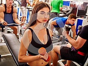 Tired girl keeps dumbbells in sport gym.