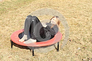 Tired girl lying on trampoline