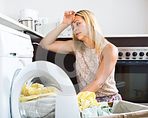 Tired girl near washing machine
