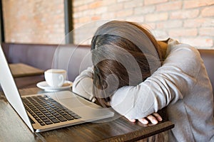 Tired girl sleeping beside a cup of coffee