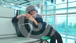 Tired girl teen in headphones traveler sleeping on the airport waiting for the plane departure lifestyle gates bench