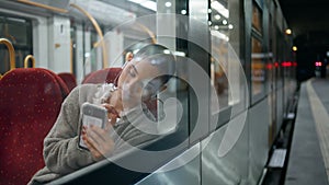 Tired girl texting smartphone in train close up. Sad short hair woman passenger