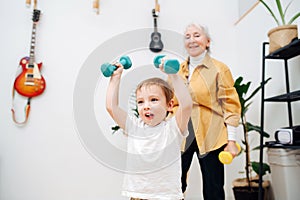 Tired granny doing phisical exercises with her grandson, tries to encourage him