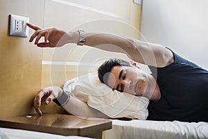 Tired Guy Switching off Light While Lying on Bed