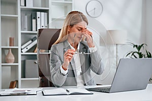 Tired, having headache. Woman in business formal clothes is working in office