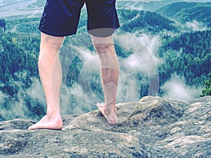 Tired hikers legs without shoes. Sandstone rock above valley.