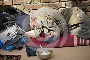 Tired homeless old man sleeping on cardboard in the street.