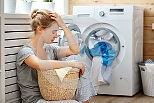 Tired housewife woman in stress sleeps in laundry room with wash photo