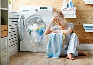 Tired housewife woman in stress sleeps in laundry room with washing machine photo