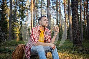 Tired hungry hiker camper man dreaming eating sandwich take break halt in forest enjoying nature.