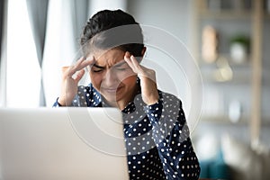 Tired Indian girl suffer from migraine at workplace