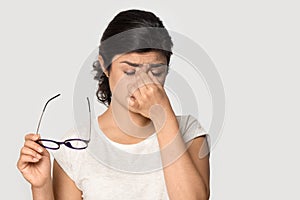 Tired Indian girl taking off glasses, feeling eye strain photo