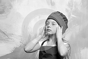 Tired kid, serious girl cook in red chef hat, apron