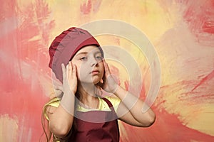 Tired kid, serious girl cook in red chef hat, apron