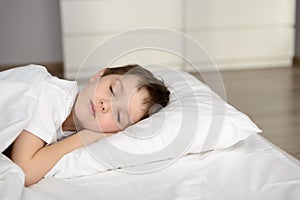 Tired kid sleeping in bed, happy bedtime in white bedroom photo