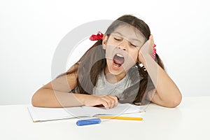 Tired kid yawning while she doing her homework