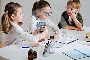 Tired kids doing home science project, girl is documenting the process