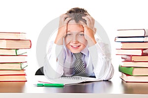 A tired, lagging schoolboy boy sits in a library with books and learns lessons. Unwillingness to learn