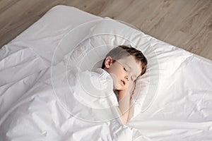 Tired little boy sleeping in bed, happy bedtime in white bedroom photo