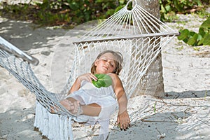 tired little girl lying and sleeping on hammock in garden