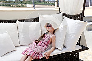 Tired little girl relaxing on terrace divan