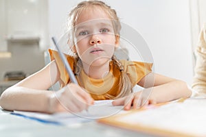 A tired little schoolgirl does her homework.