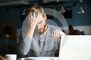 Tired male annoyed with difficult studying sitting in cafe