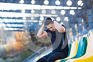 Tired male athlete resting, Asian holding his head, has a severe headache after running
