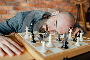 Tired male chess player sleeping on the board