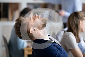 Tired male employee falling asleep in chair at workplace