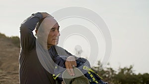 Tired male hiker sitting on ground and relaxing after climbing