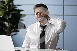 Tired male office worker suffer from backache at workplace