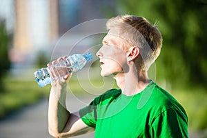 Tired man drinking water from a plastic bottle