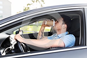 Tired man driving car and drinking coffee