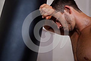 Tired man leaning on punching bag