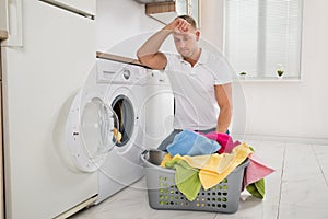 Tired Man Loading Clothes Into The Washing Machine