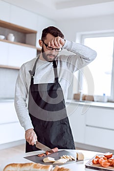 Tired man makes sandwiches in his kitchen