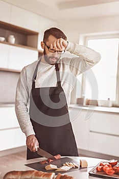 Tired man makes sandwiches in his kitchen