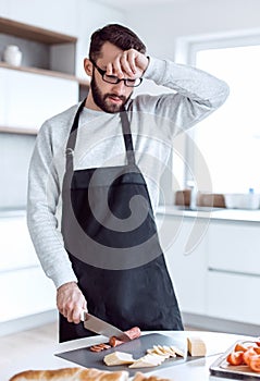 Tired man makes sandwiches in his kitchen