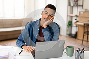 Tired man napping in front of laptop