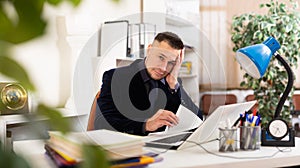 Tired man office worker sitting at table