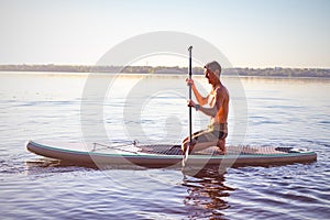 Tired man paddling on a SUP board on large river