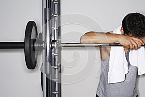 Tired Man Resting On Barbell At Gym