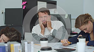 Tired man sit a table and clap his face to continue to work