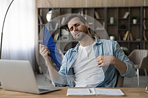 Tired man suffer from hot weather wave with hand fan